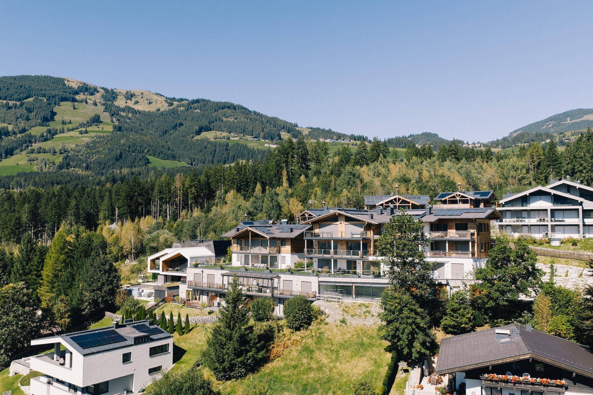 Panoramablick auf eine exklusive Wohnanlage in alpiner Landschaft mit modernen Gebäuden und viel Grün.
