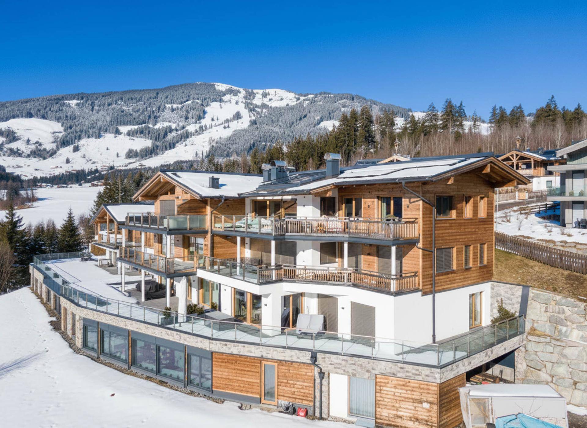 Modernes Chalet-Gebäude in den Bergen mit mehreren Balkonen und Terrassen im Winter.