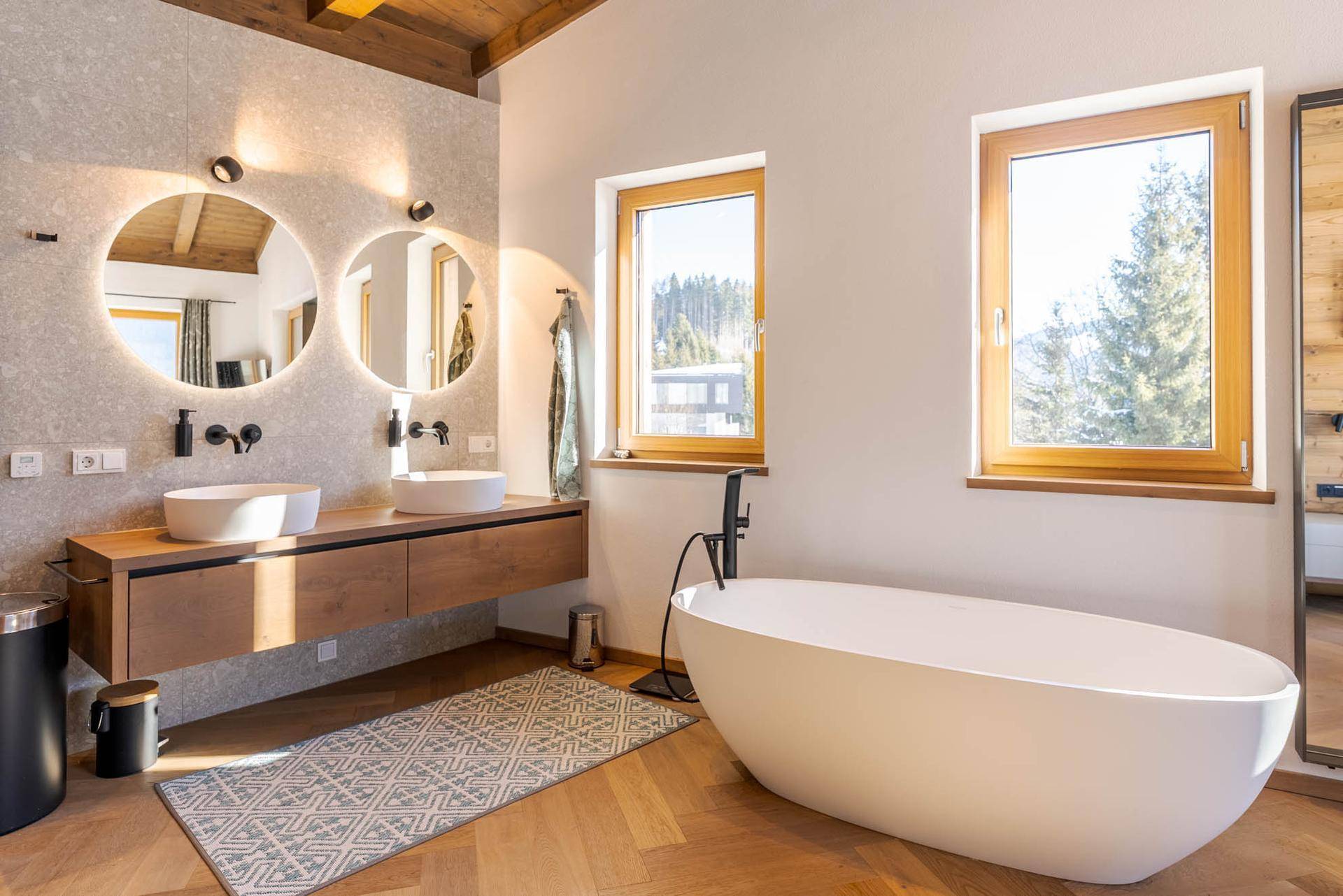 Helles Badezimmer mit freistehender Badewanne, Doppelwaschbecken und Bergblick.