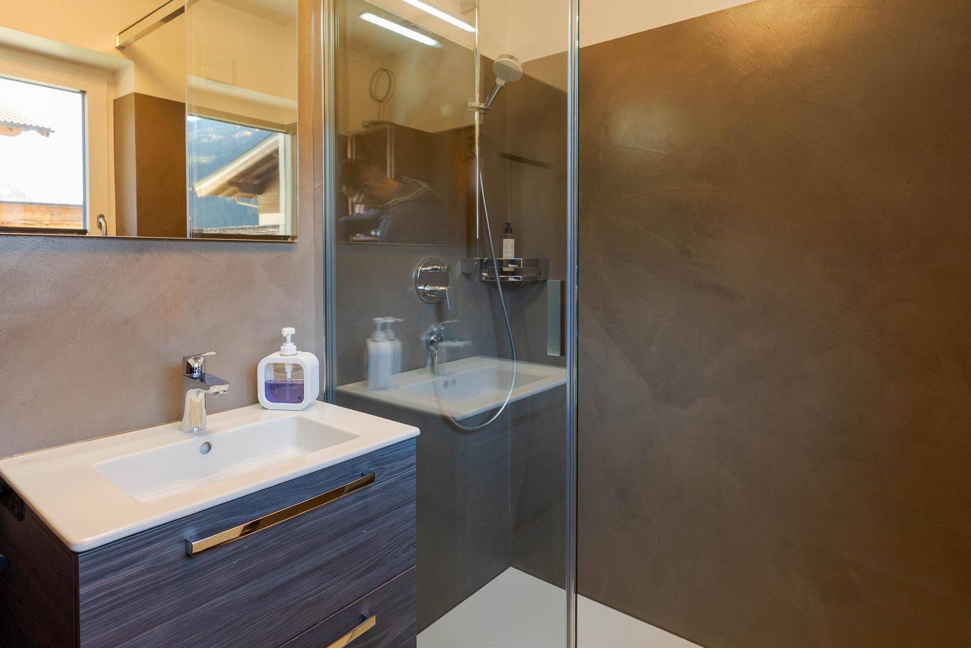 Modernes Badezimmer mit Einzelwaschbecken, Spiegelschrank und begehbarer Dusche.