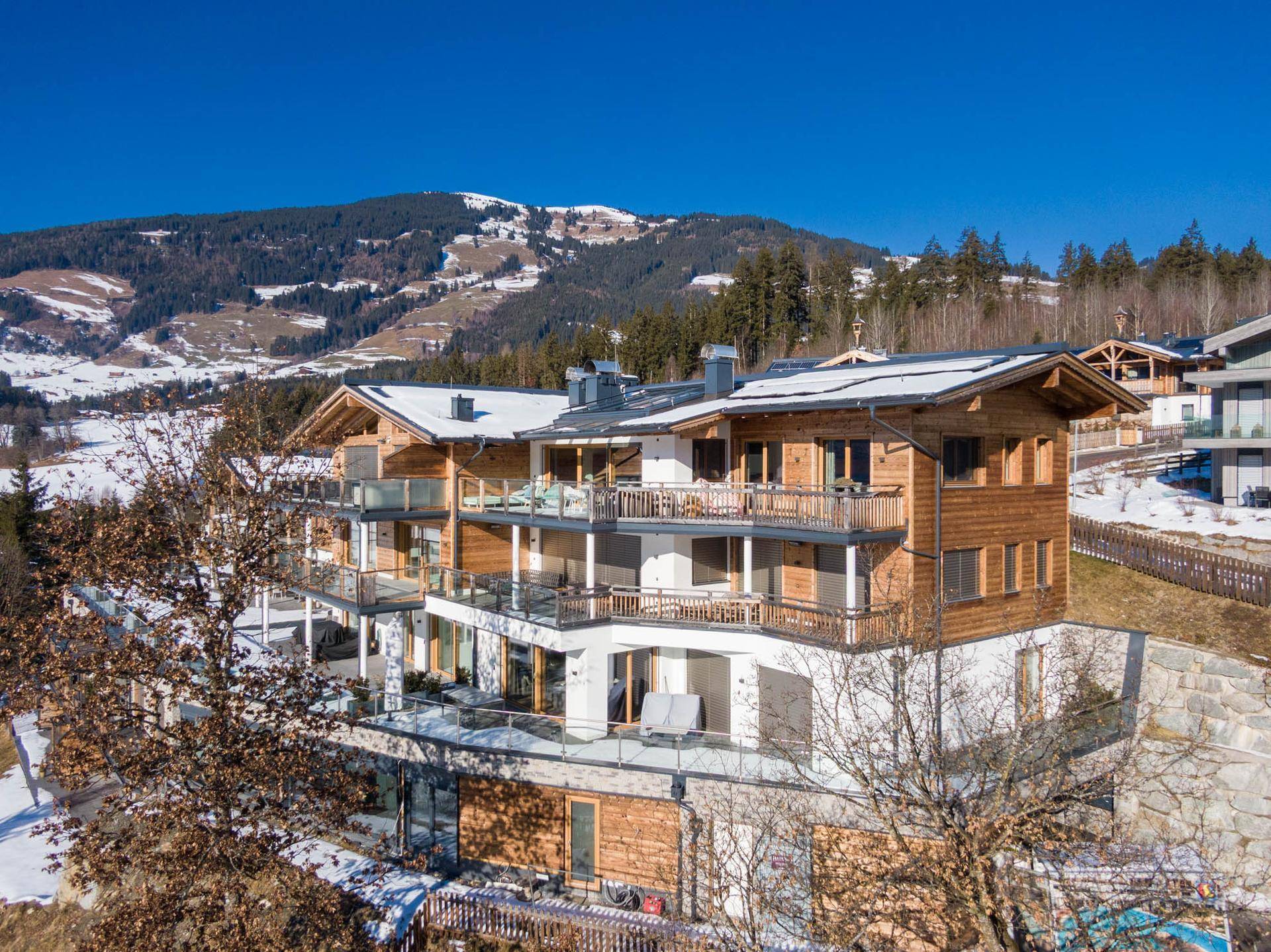 Modernes Chalet-Gebäude in den Bergen mit mehreren Balkonen und Terrassen im Winter.
