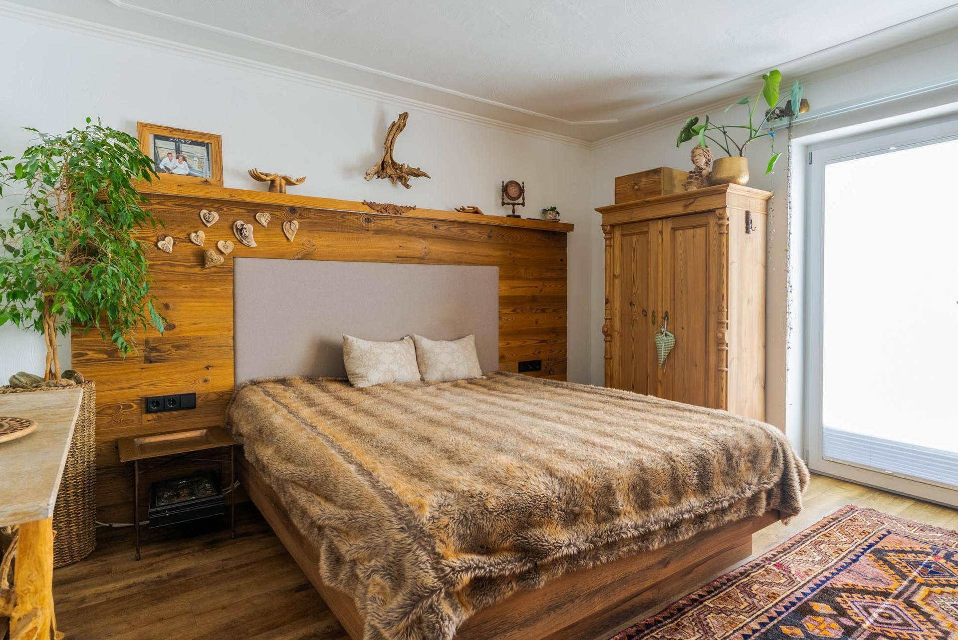 Rustikales Schlafzimmer mit Holzbett, flauschiger Decke und traditionellem Teppich.