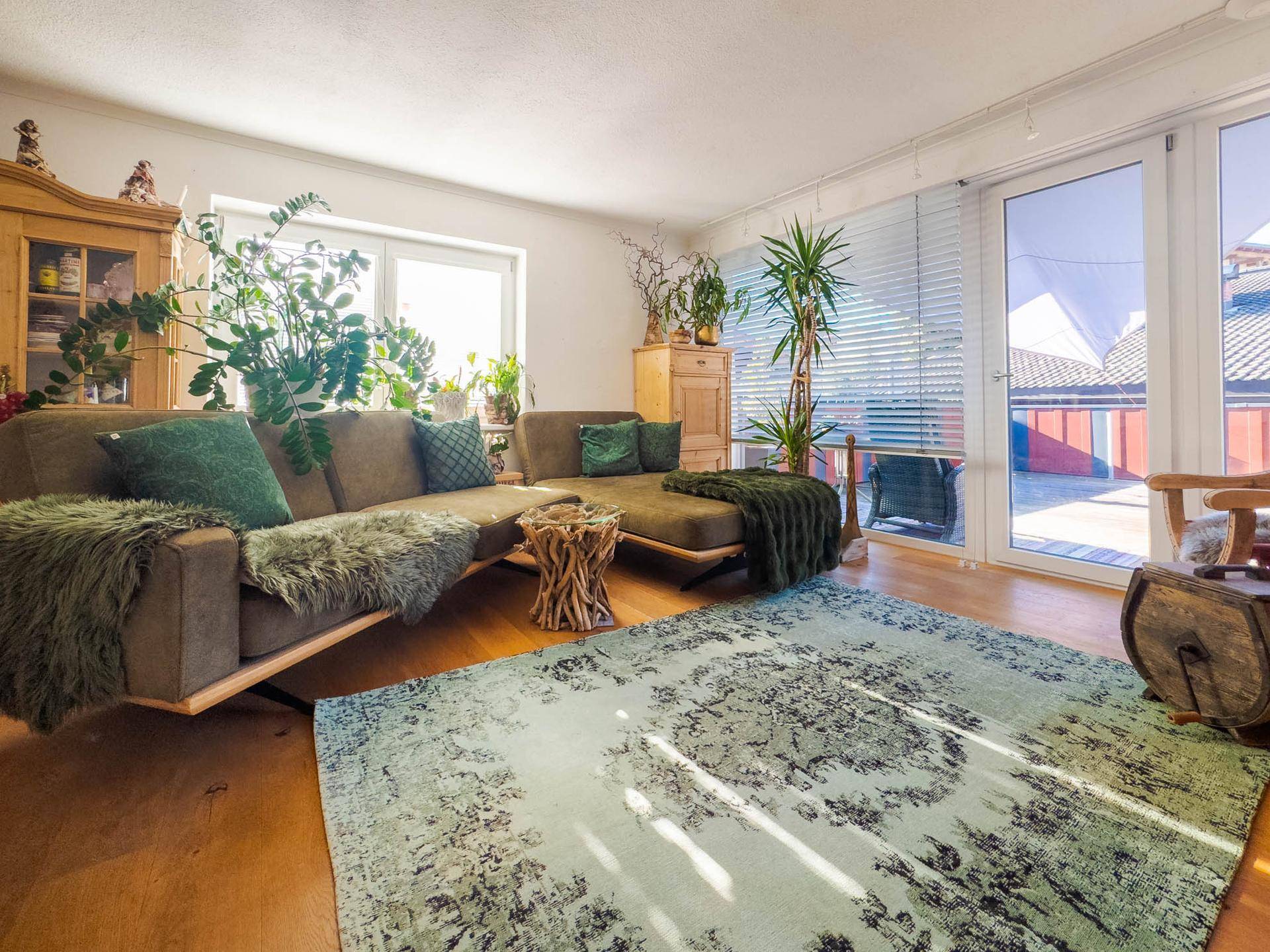 Helles Wohnzimmer mit Holzboden, bequemer Couch und Zugang zu einer großen Terrasse.