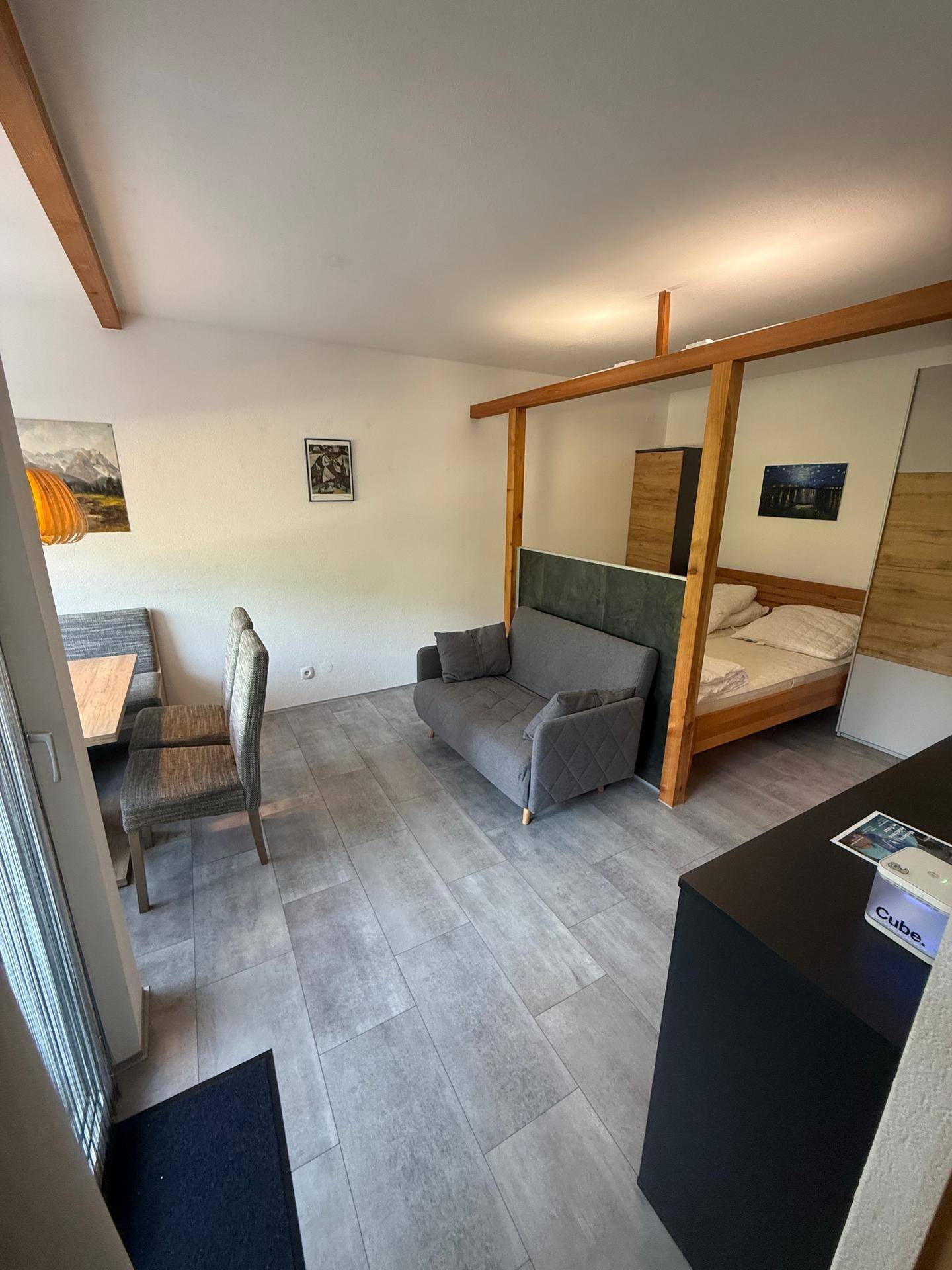 Offener Wohnbereich mit Schlafsofa, Essbereich und Zugang zum Balkon.