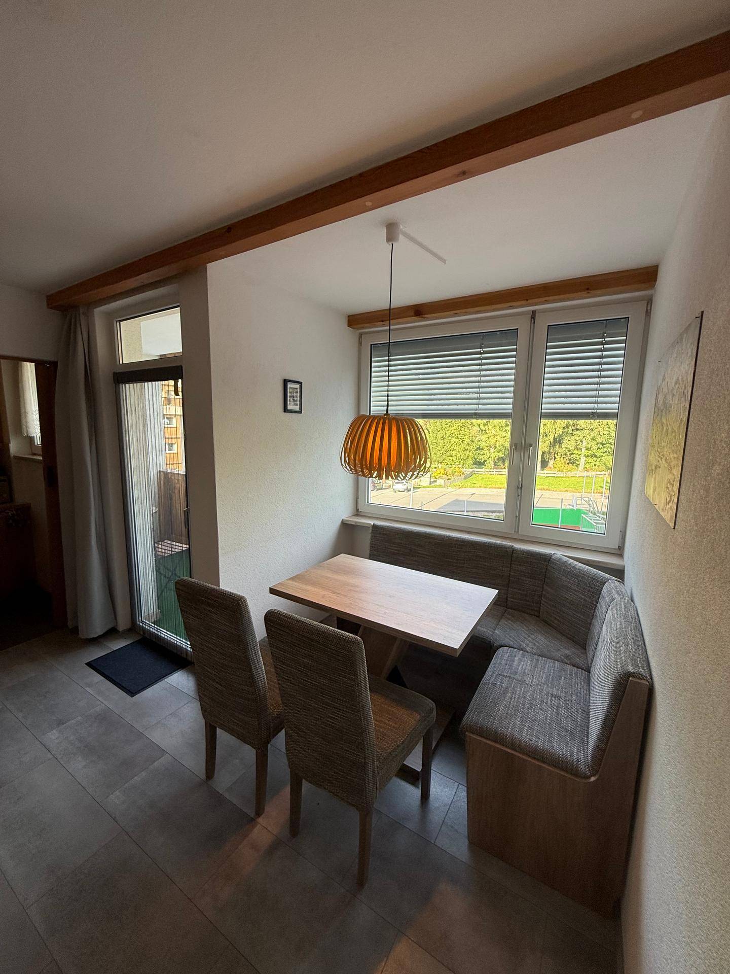 Gemütlicher Essbereich mit Eckbank, Holztisch und großem Fenster mit Blick ins Grüne.