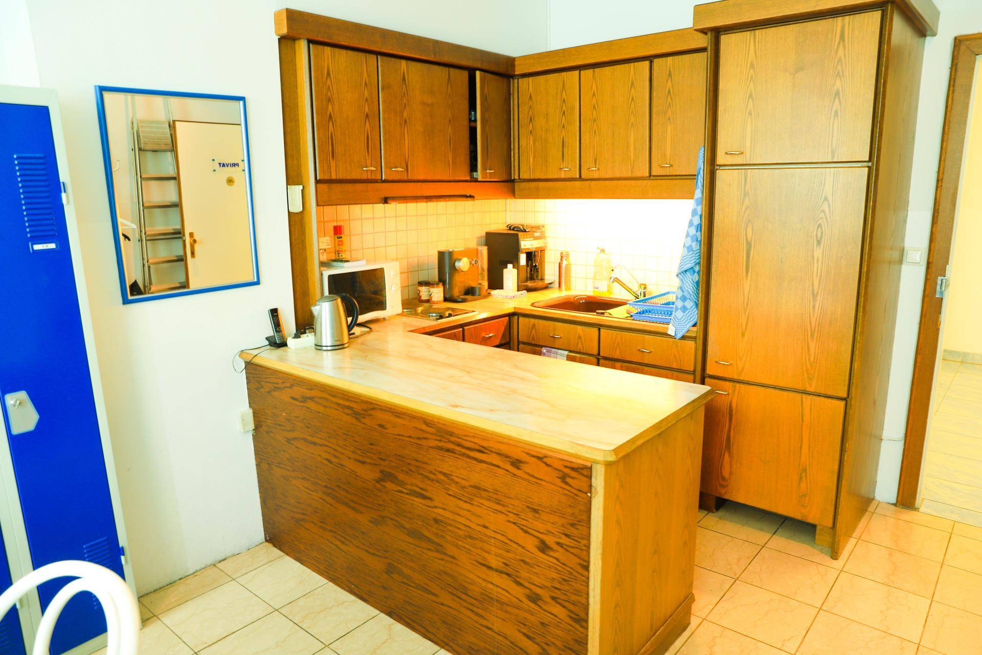 Kleine Küche mit Holzschränken, Arbeitsplatte und integrierten Geräten in einem älteren Stil.