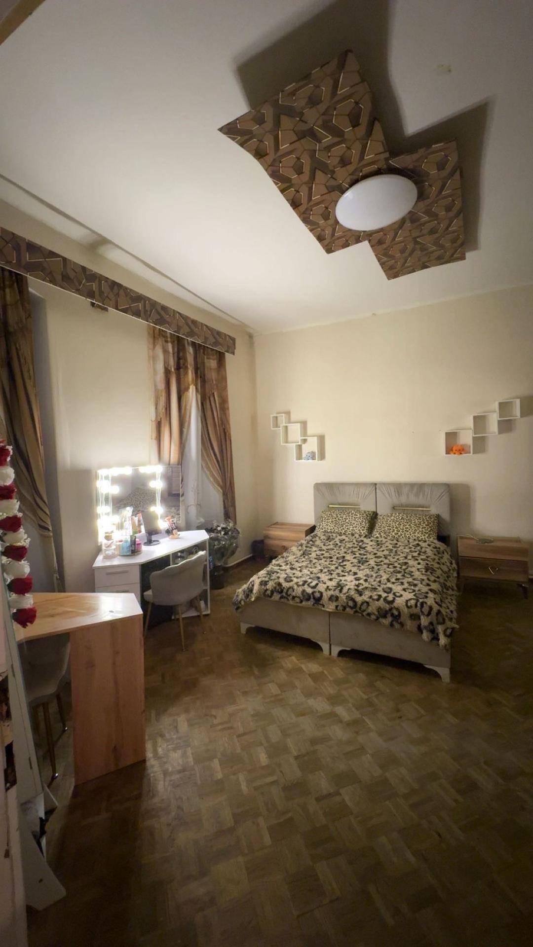 Helles Schlafzimmer mit Doppelbett, Schminktisch mit beleuchtetem Spiegel und Holzboden.