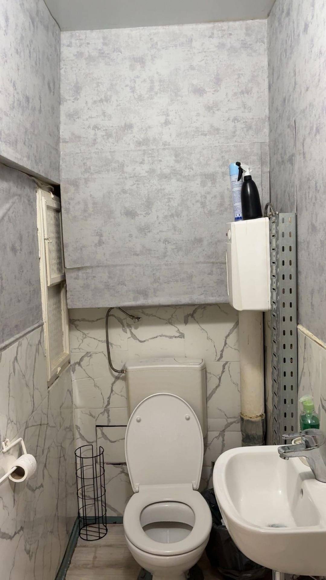 Kleine Gästetoilette mit WC, Waschbecken und gefliesten Wänden in hellem Design.