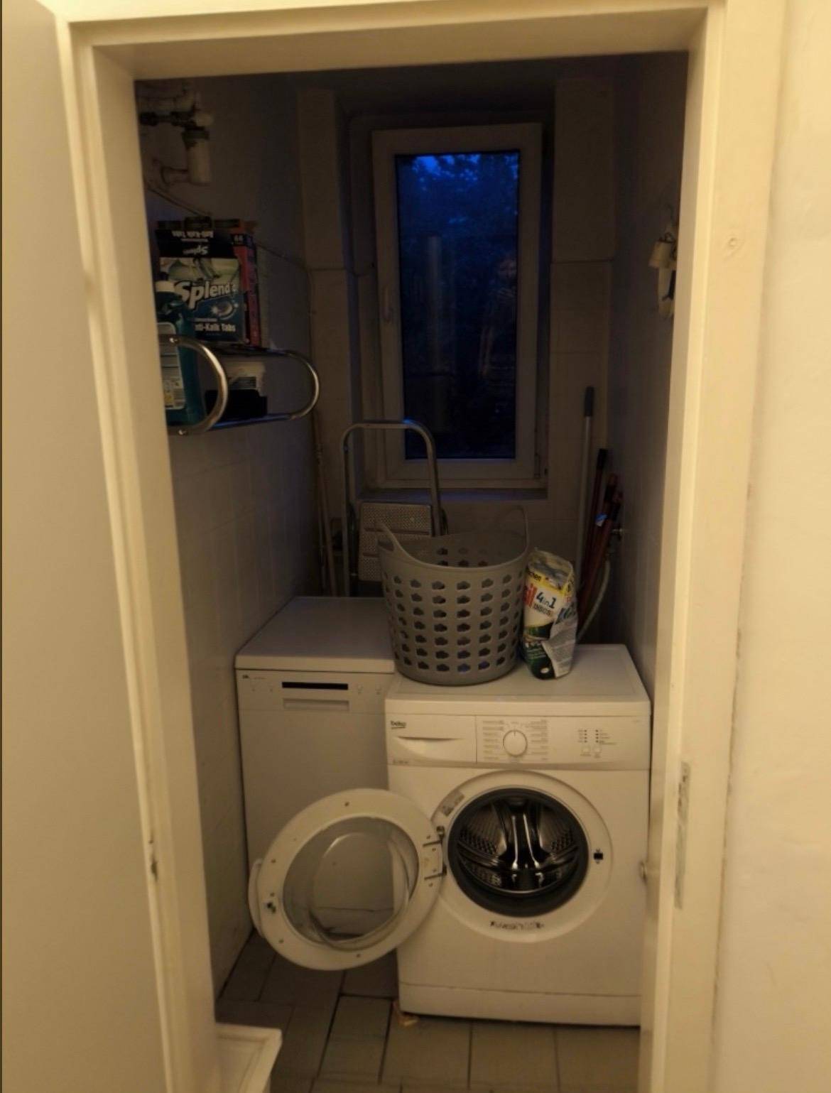 Kleiner Hauswirtschaftsraum mit Waschmaschine, Trockner und Fenster, praktisch eingerichtet.