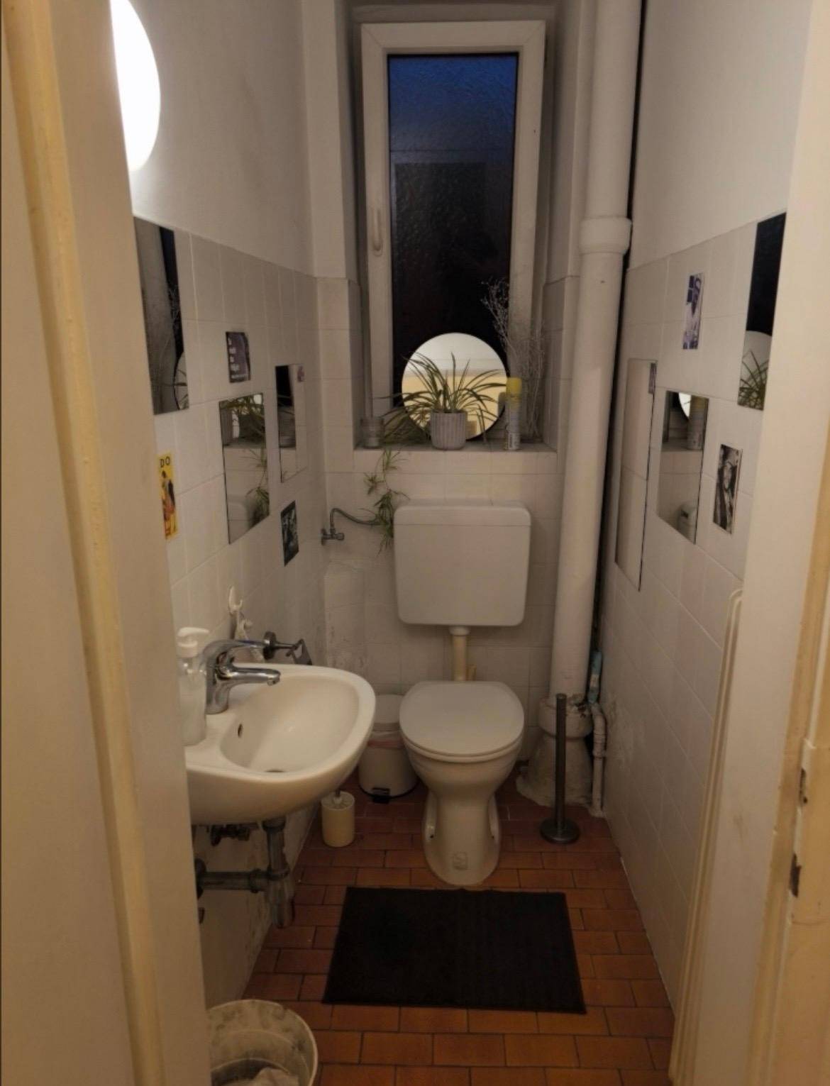 Kleines WC mit Fenster, Waschbecken und Toilette, einfach und funktional ausgestattet.
