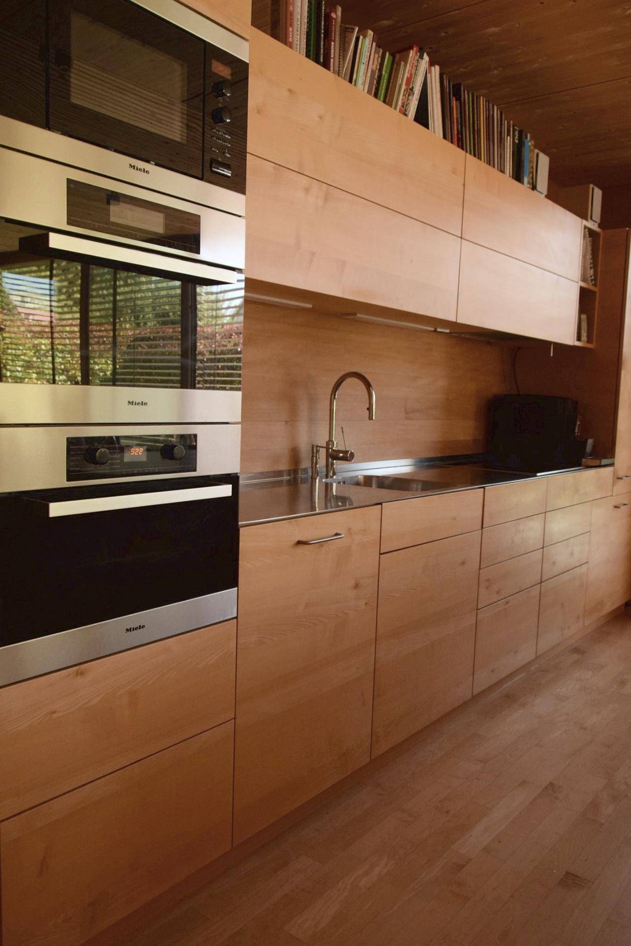 Moderne Einbauküche mit Holzfronten und integrierten Miele-Geräten.