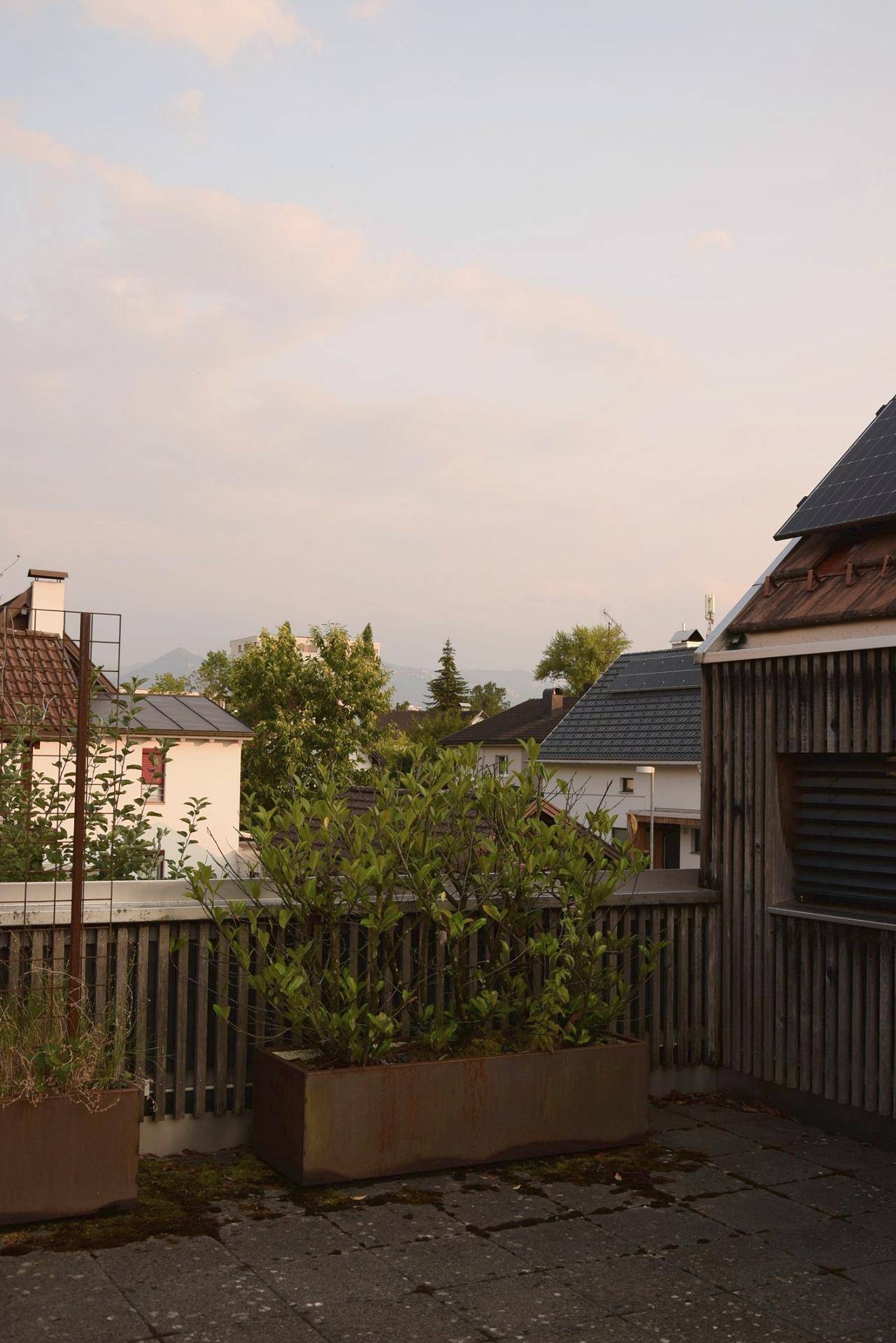 Dachterrasse mit Blick auf die umliegende Wohnbebauung und entfernte Berge.