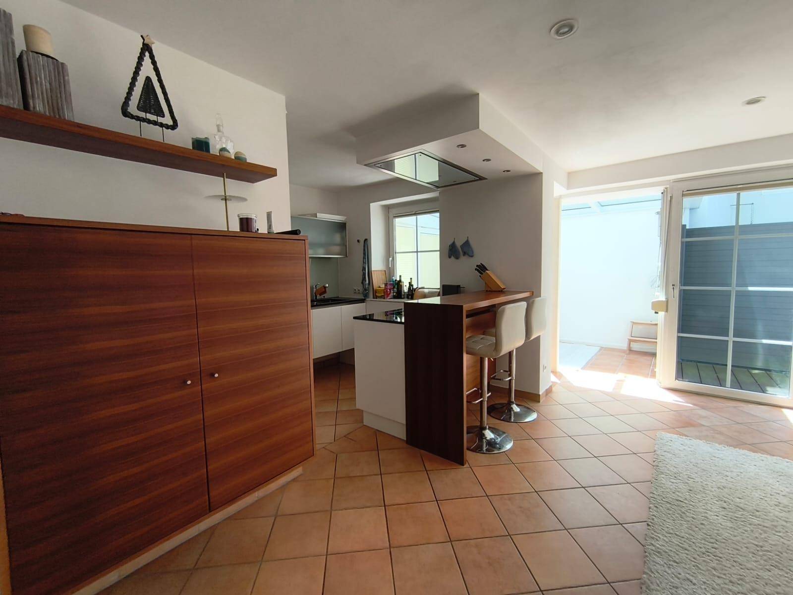 Offener Wohn- und Essbereich mit Küchenzeile, Bar und Terracottaboden.