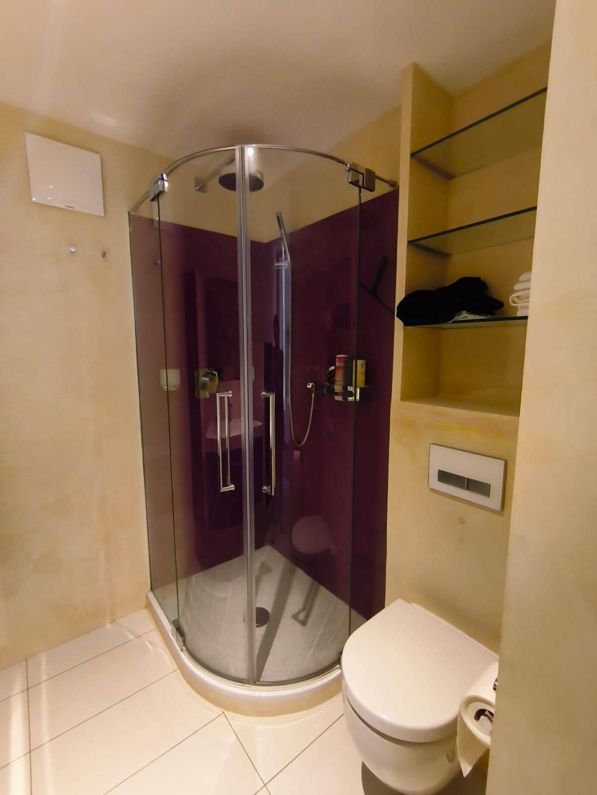 Modernes Badezimmer mit Duschkabine, Wand-WC und beigefarbenen Fliesen.