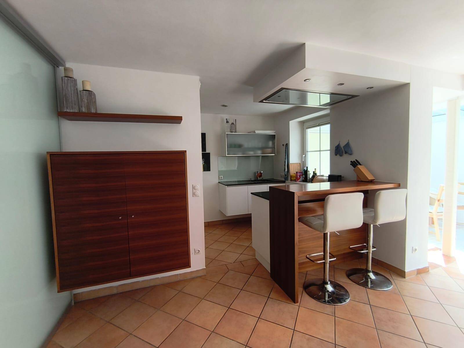 Offener Wohnbereich mit Küchenzeile, Bar und Terracottaboden.
