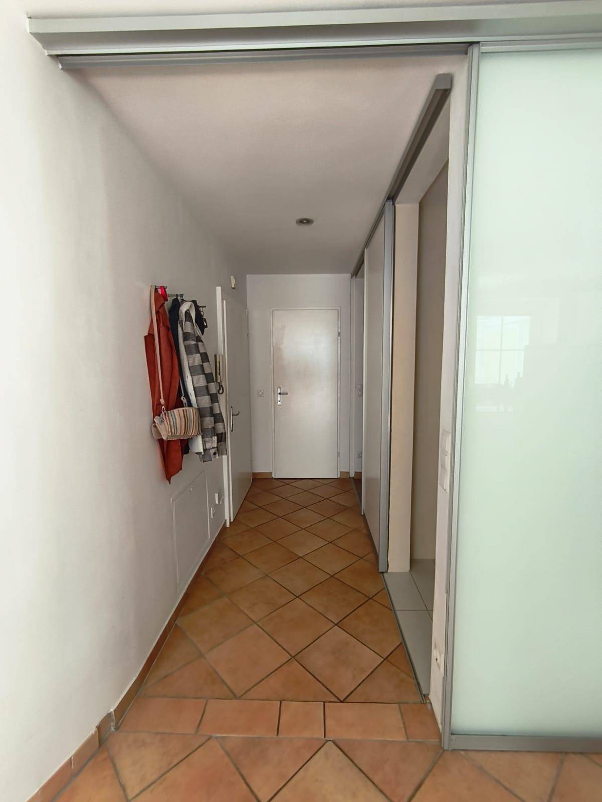 Flur mit Terracottaboden, Garderobe und Schiebetüren.