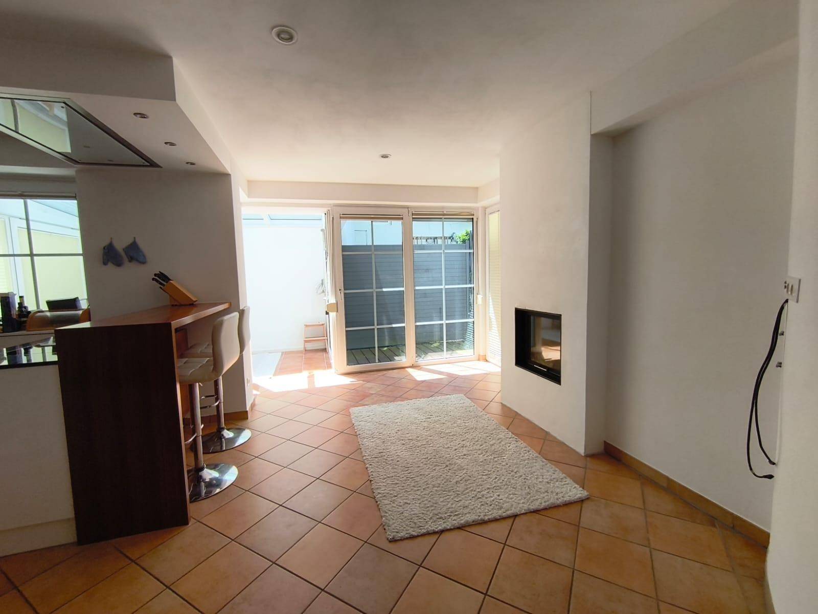 Offener Wohnbereich mit Kamin, Terracottaboden und Zugang zum Wintergarten.