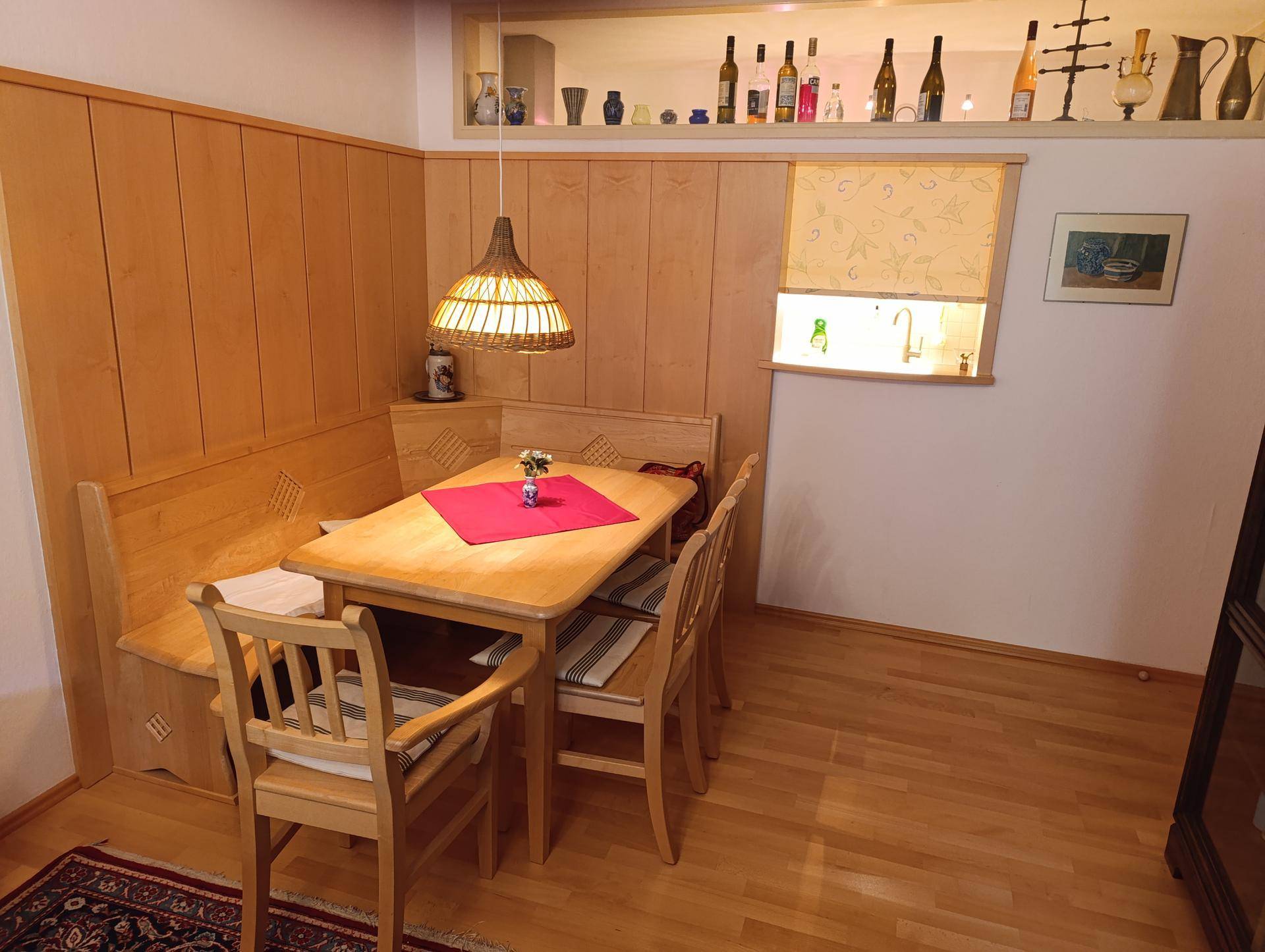 Traditioneller Essbereich mit Holztisch, Eckbank und Holzvertäfelung, gemütlich beleuchtet.