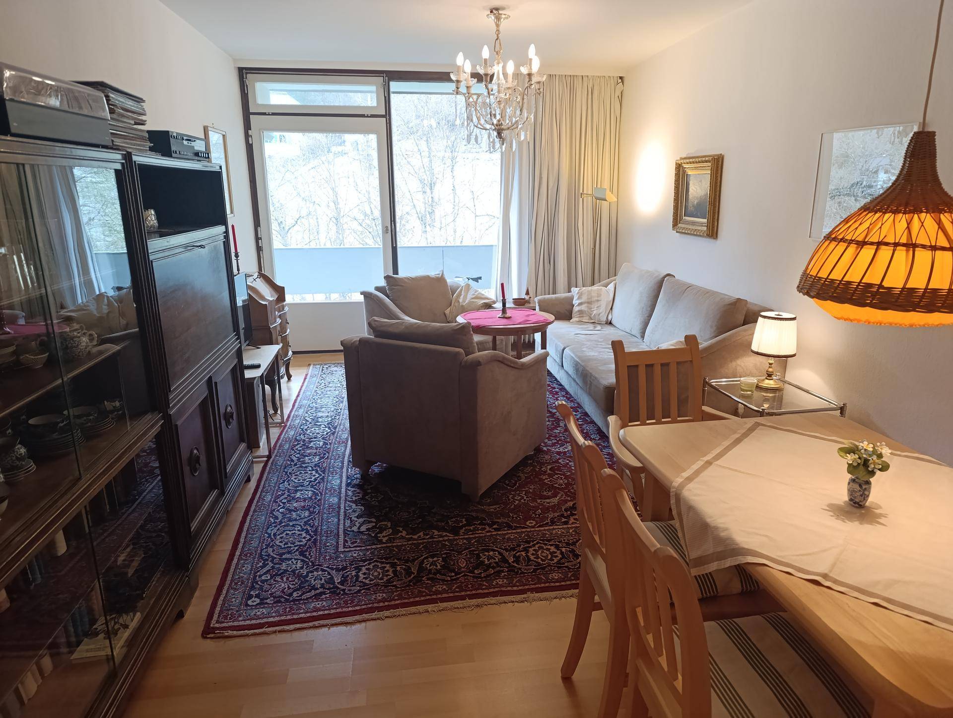 Gemütlicher Wohn-Essbereich mit Holzboden, bequemen Sofas und Zugang zu einem Balkon mit Tageslicht.