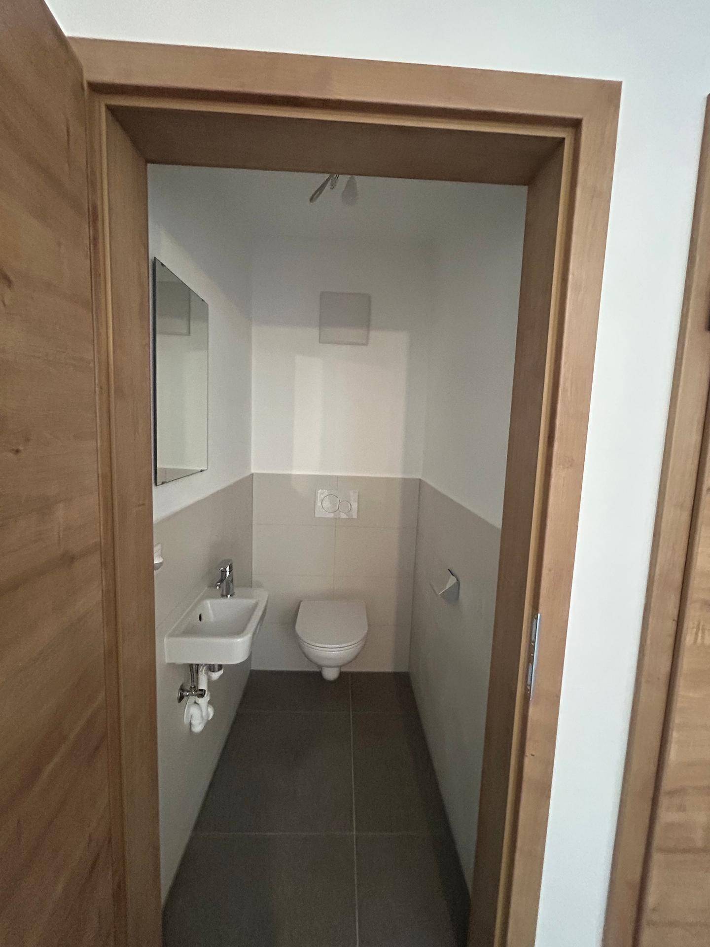 Kompaktes Gäste-WC mit modernem Waschbecken, Toilette und hellen Wandfliesen, sehr sauber und funktional.