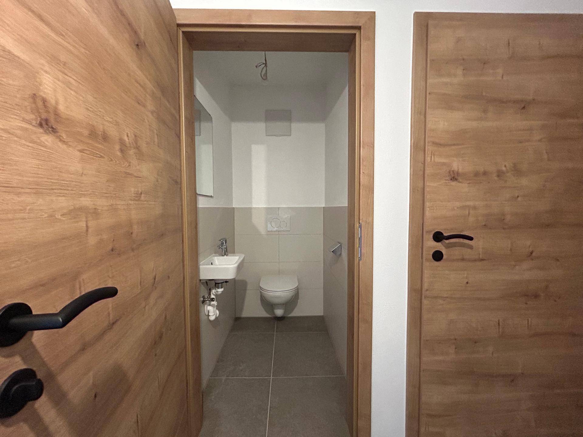Sauberes Gäste-WC mit modernem Design, kleinem Waschbecken und Wand-WC, sehr platzsparend und stilvoll.