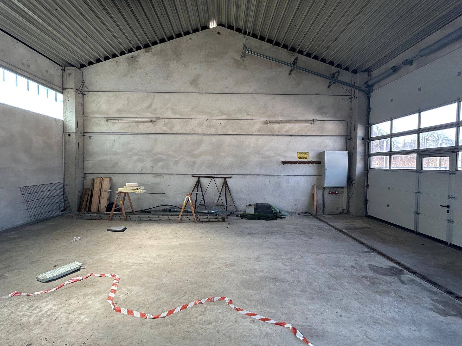 Großer, heller Lagerraum mit Betonboden und sichtbaren Installationen an den Wänden, ideal für gewerbliche Zwecke.