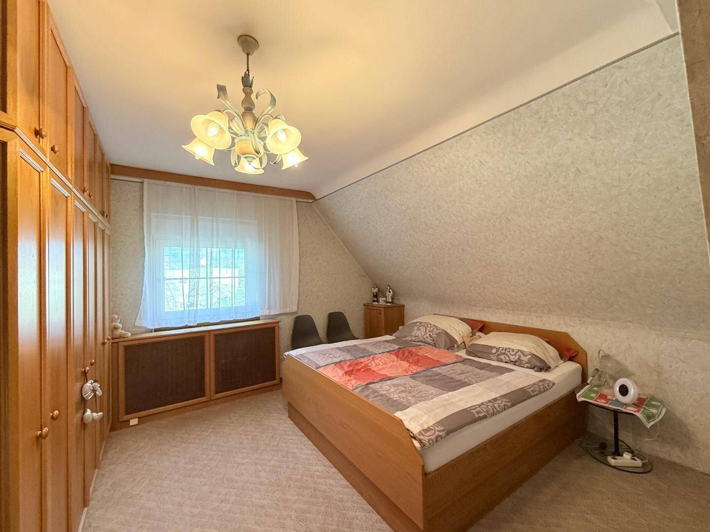 Gemütliches Schlafzimmer mit Dachschräge, Einbauschränken aus Holz und einem Doppelbett.