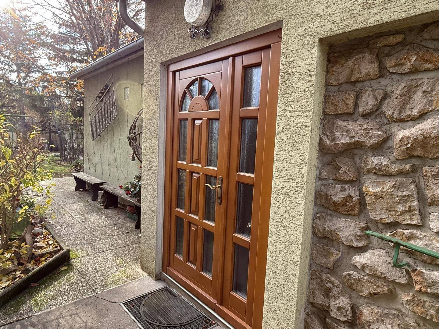 Detailansicht einer traditionellen Holzeingangstür mit Glaseinsätzen und Natursteinmauerwerk.