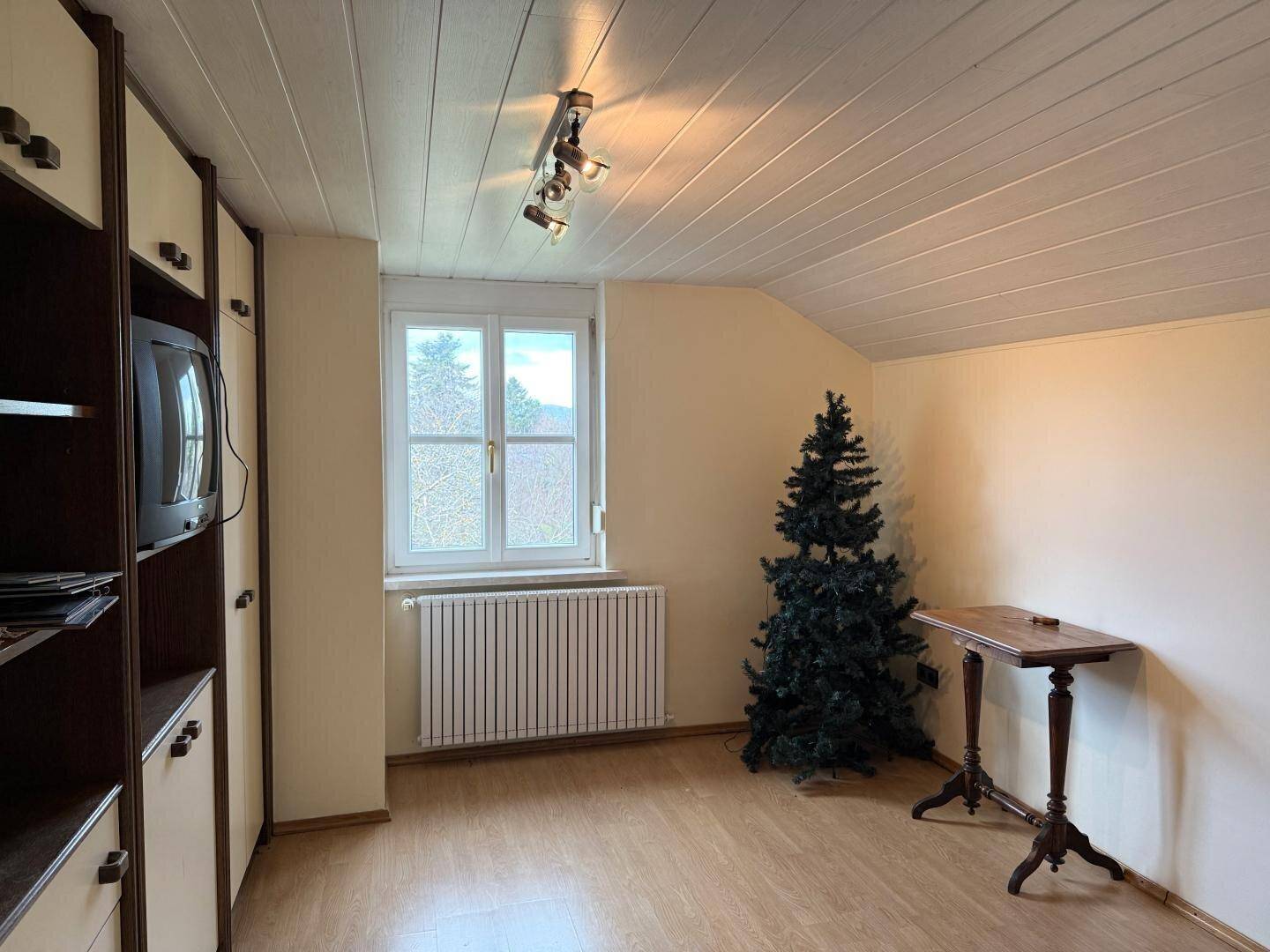 Schlafzimmer mit Dachschräge, Einbauschrank und Fenster.