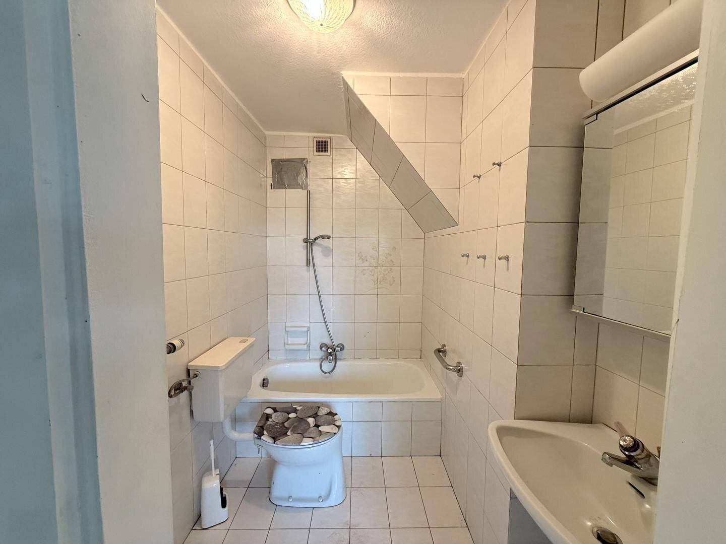 Badezimmer mit Badewanne, Toilette und Waschbecken unter Dachschräge.