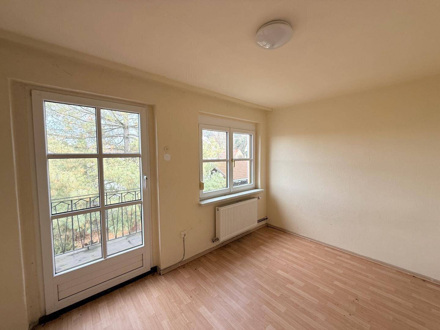 Helles Zimmer mit Balkonzugang und Laminatboden.