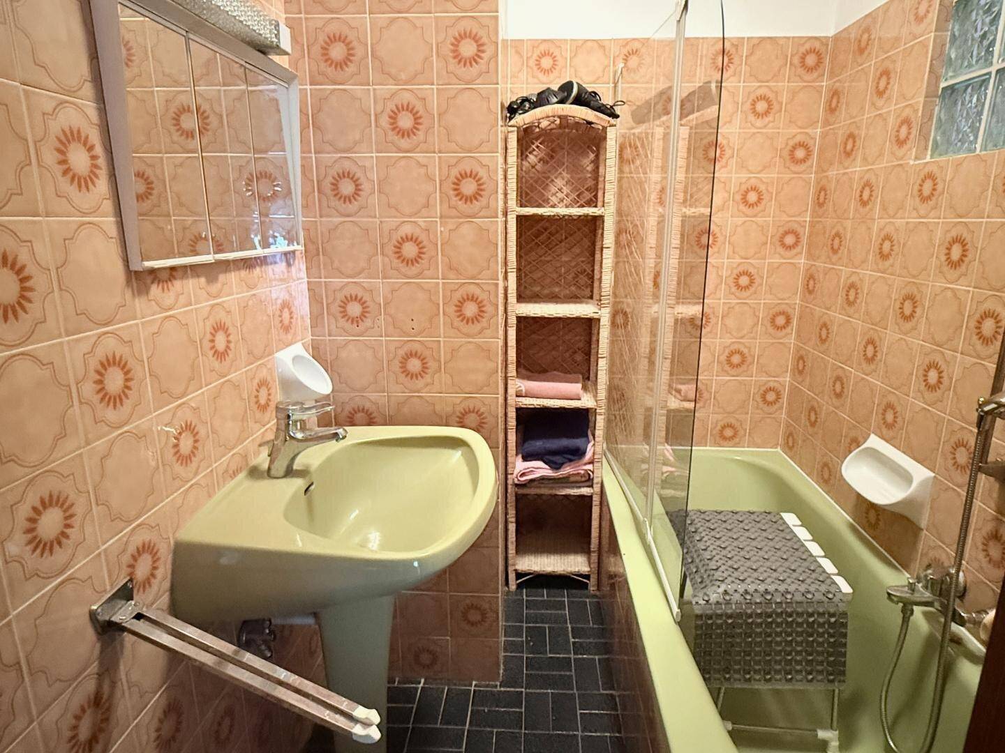 Badezimmer im 80er-Jahre-Stil mit orangefarbenen Fliesen, gelber Badewanne und Waschbecken.