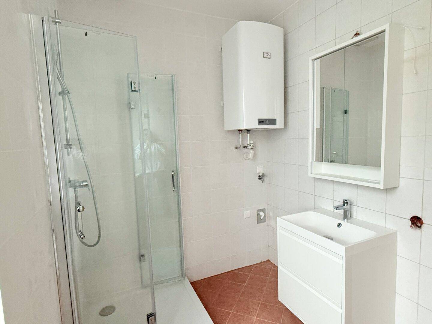 Modernes Badezimmer mit Duschkabine, Waschbecken und weißem Fliesenspiegel, in gutem Zustand.