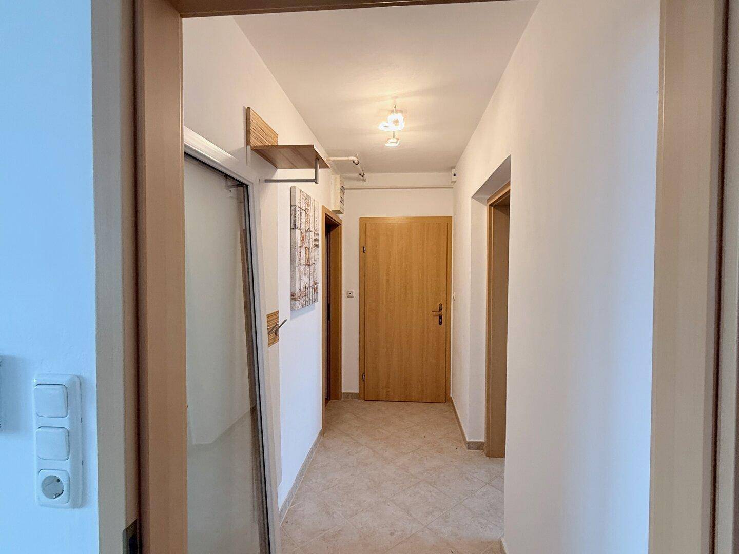 Heller Flur mit Fliesenboden, Holztüren und schlichten Wanddekorationen, einladend gestaltet.