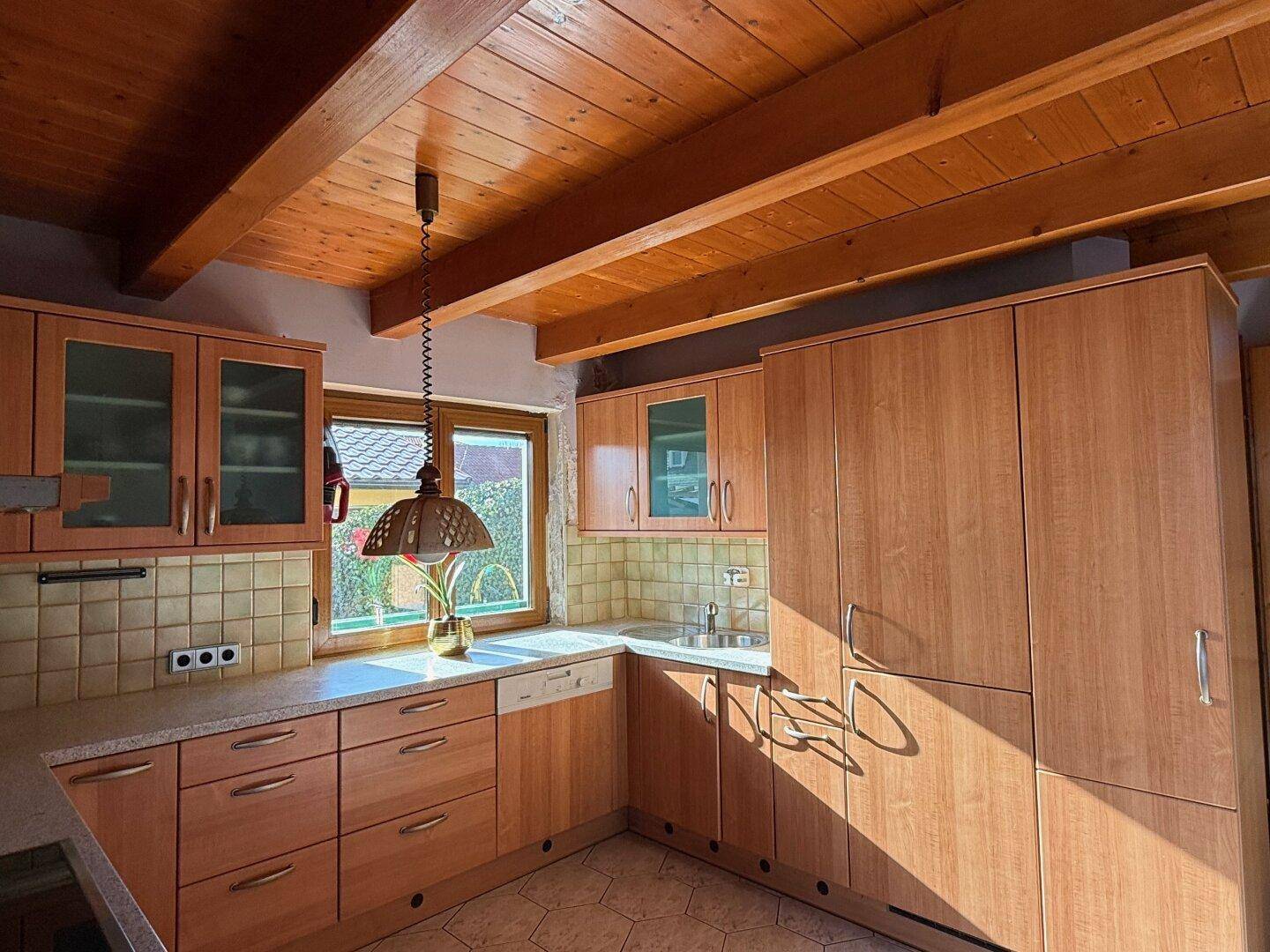 Funktionale Holzküche mit Einbaugeräten, Spülmaschine und Fenster für natürliches Licht.