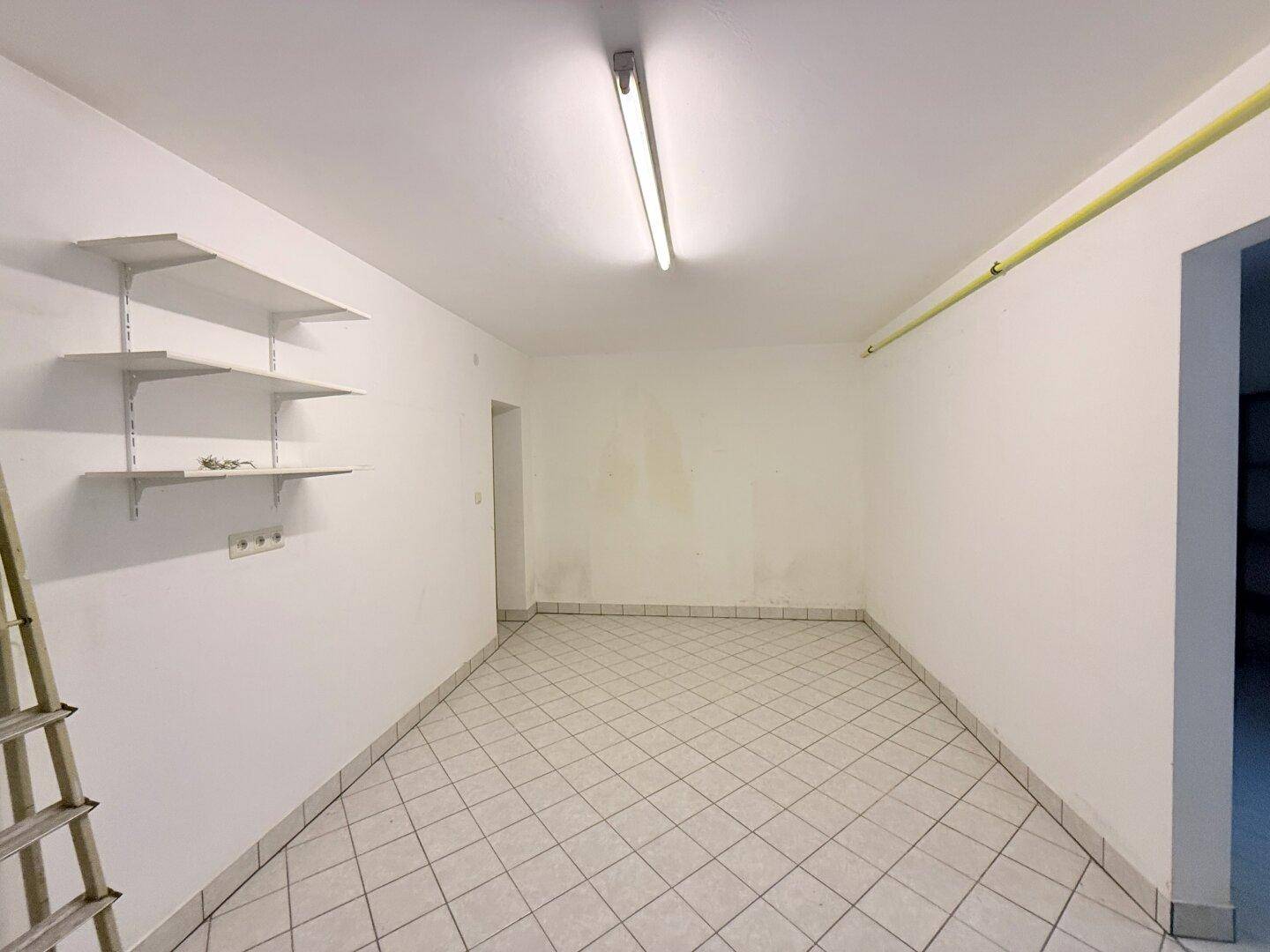 Einfacher Abstellraum mit Fliesenboden und praktischen Wandregalen für zusätzlichen Stauraum.