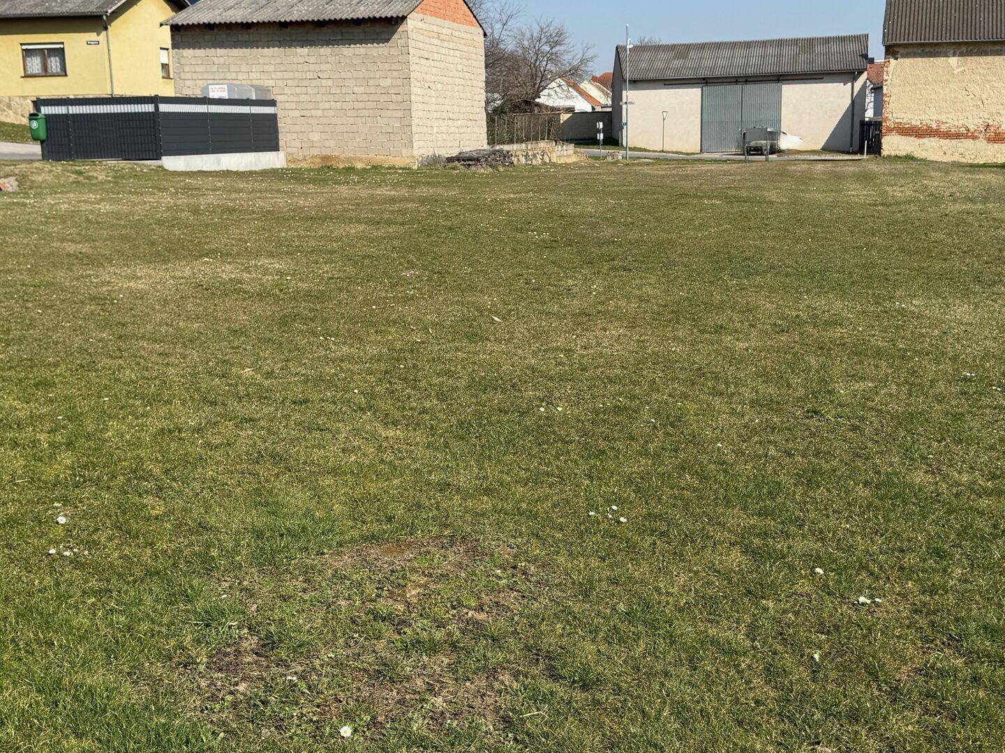 Großes, sonniges Grundstück mit Grasfläche, umgeben von verschiedenen ländlichen Gebäuden.