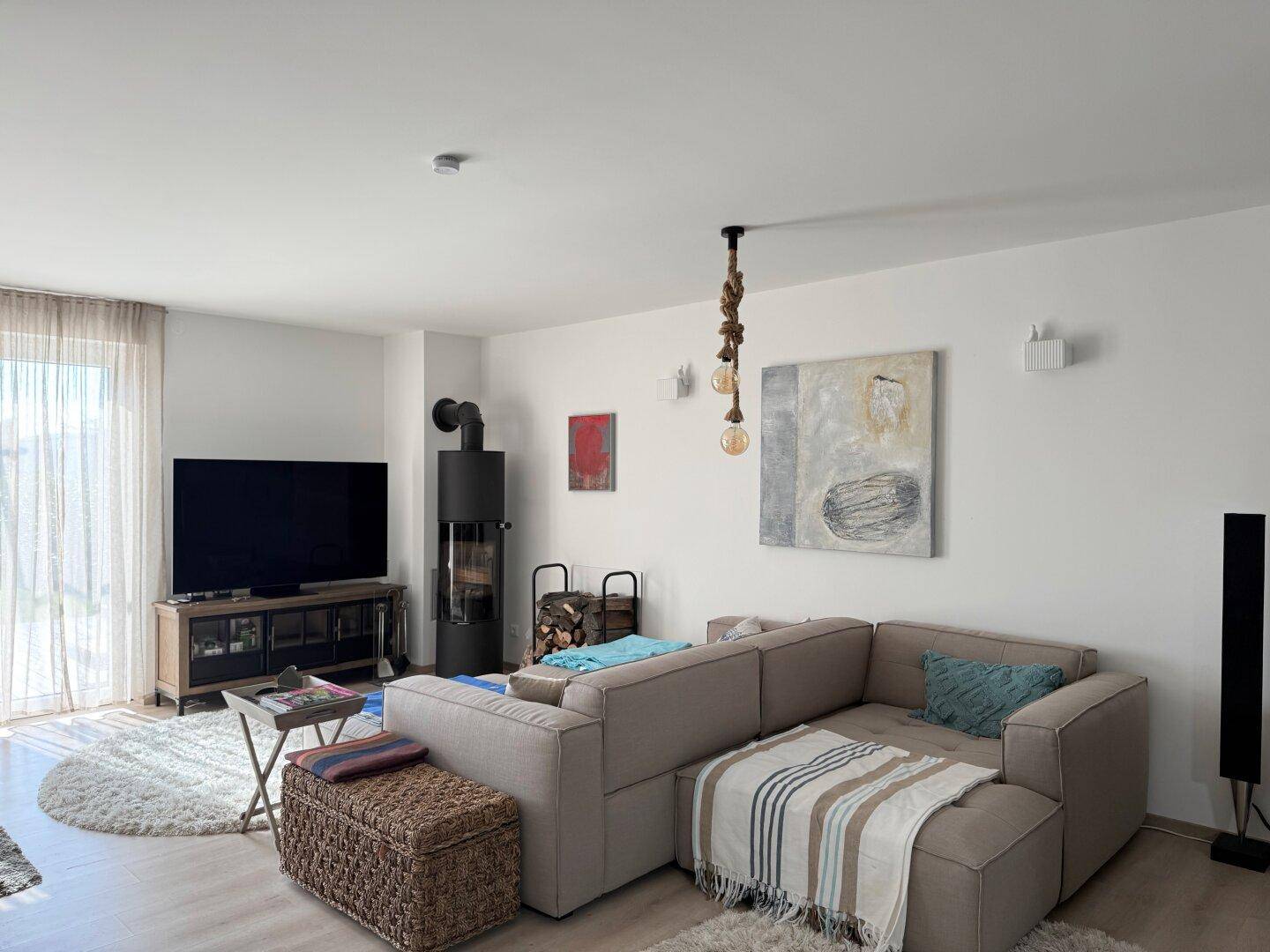 Gemütliches Wohnzimmer mit Ecksofa, Kaminofen und Zugang zu einem Außenbereich.