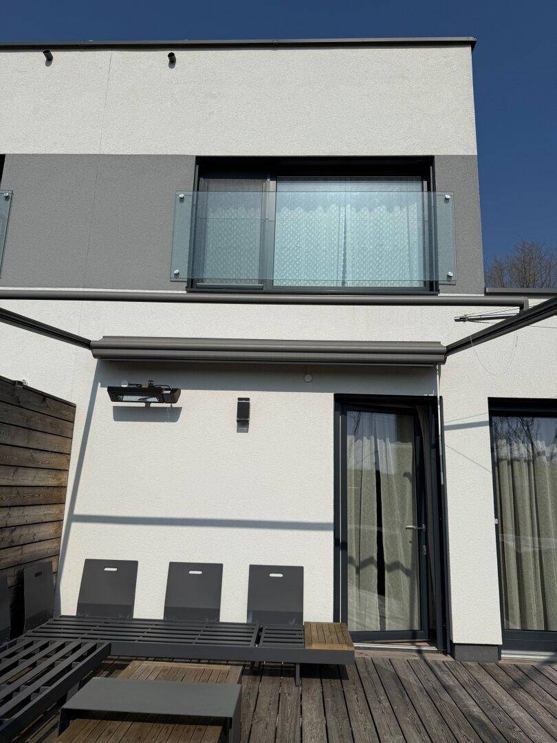 Terrasse mit Holzboden, Sitzgelegenheiten und Zugang zum Haus.