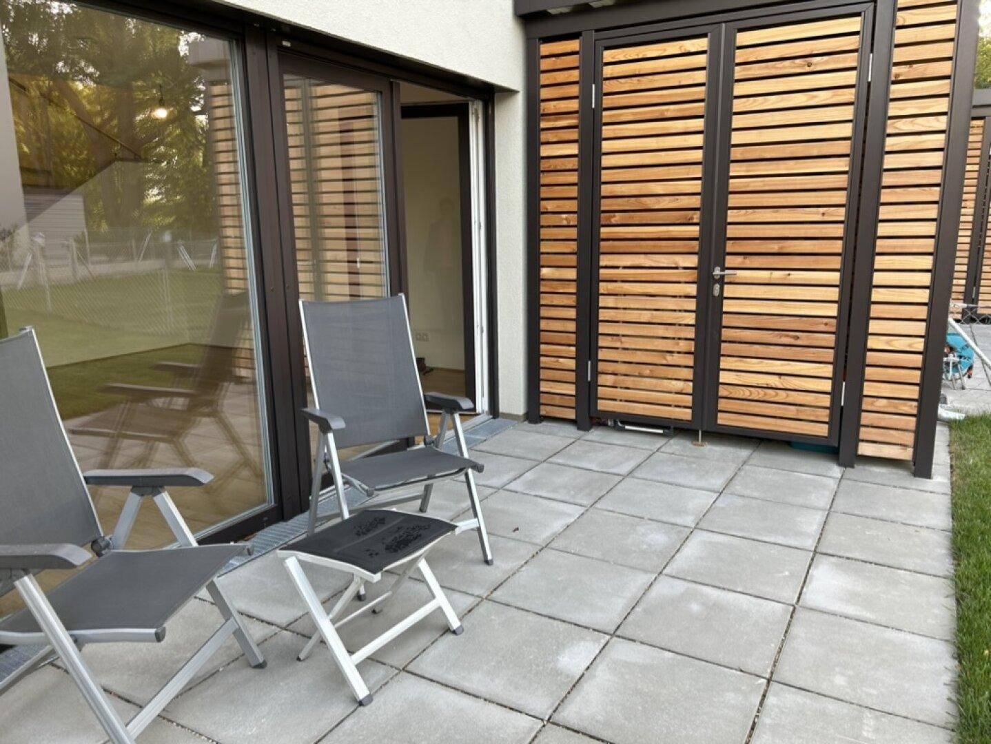 Gepflasterte Terrasse mit Sitzgelegenheiten und Zugang zum Innenbereich.