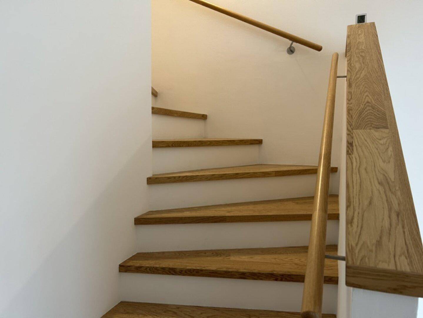 Holztreppe mit passendem Geländer und weißen Wänden.