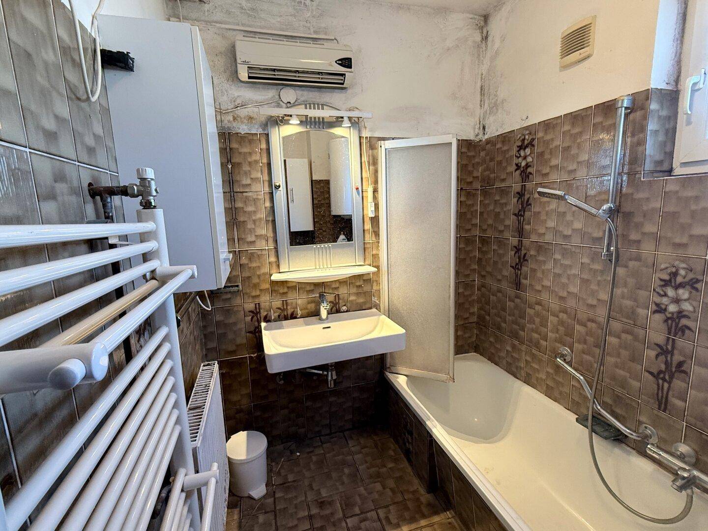 Badezimmer mit Badewanne, Waschbecken, Spiegelschrank und braunen Fliesen im traditionellen Stil.