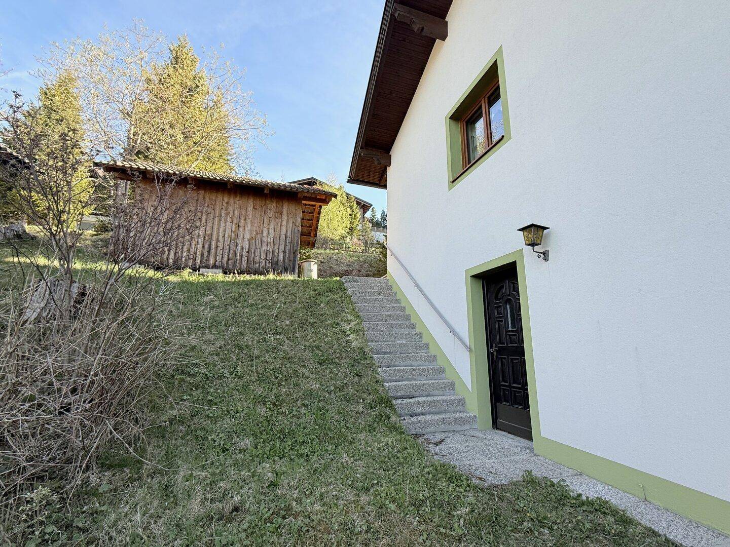 Seitenansicht des Hauses mit Außentreppe und Zugang zum Gartenbereich.