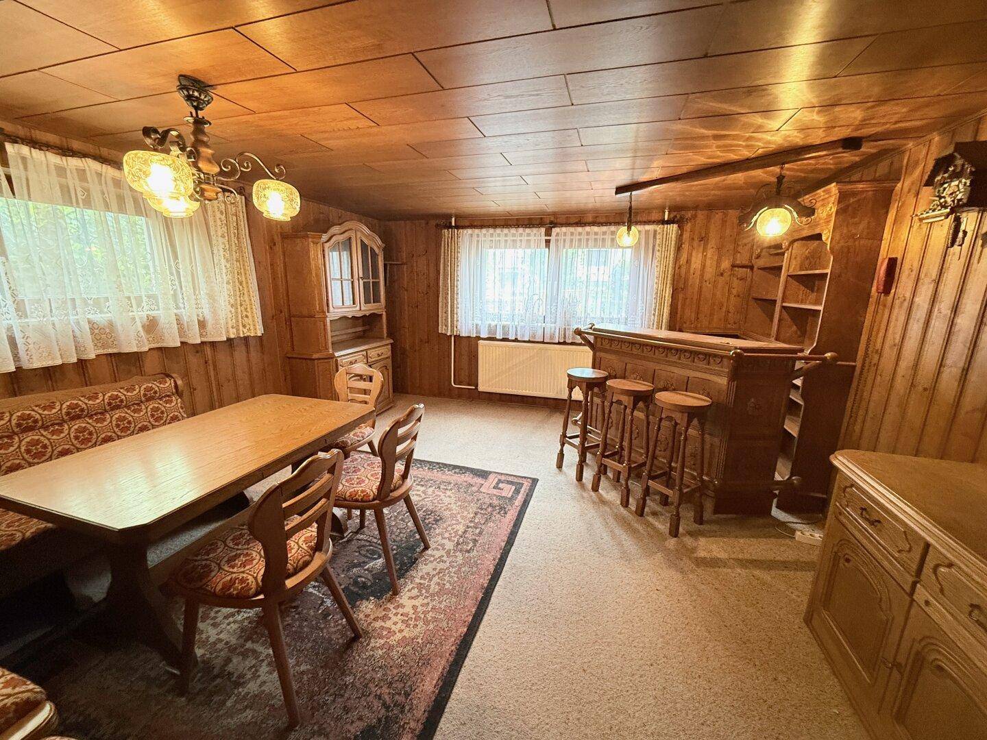 Rustikaler Wohnbereich mit Holzvertäfelung, Essbereich und einer traditionellen Hausbar.