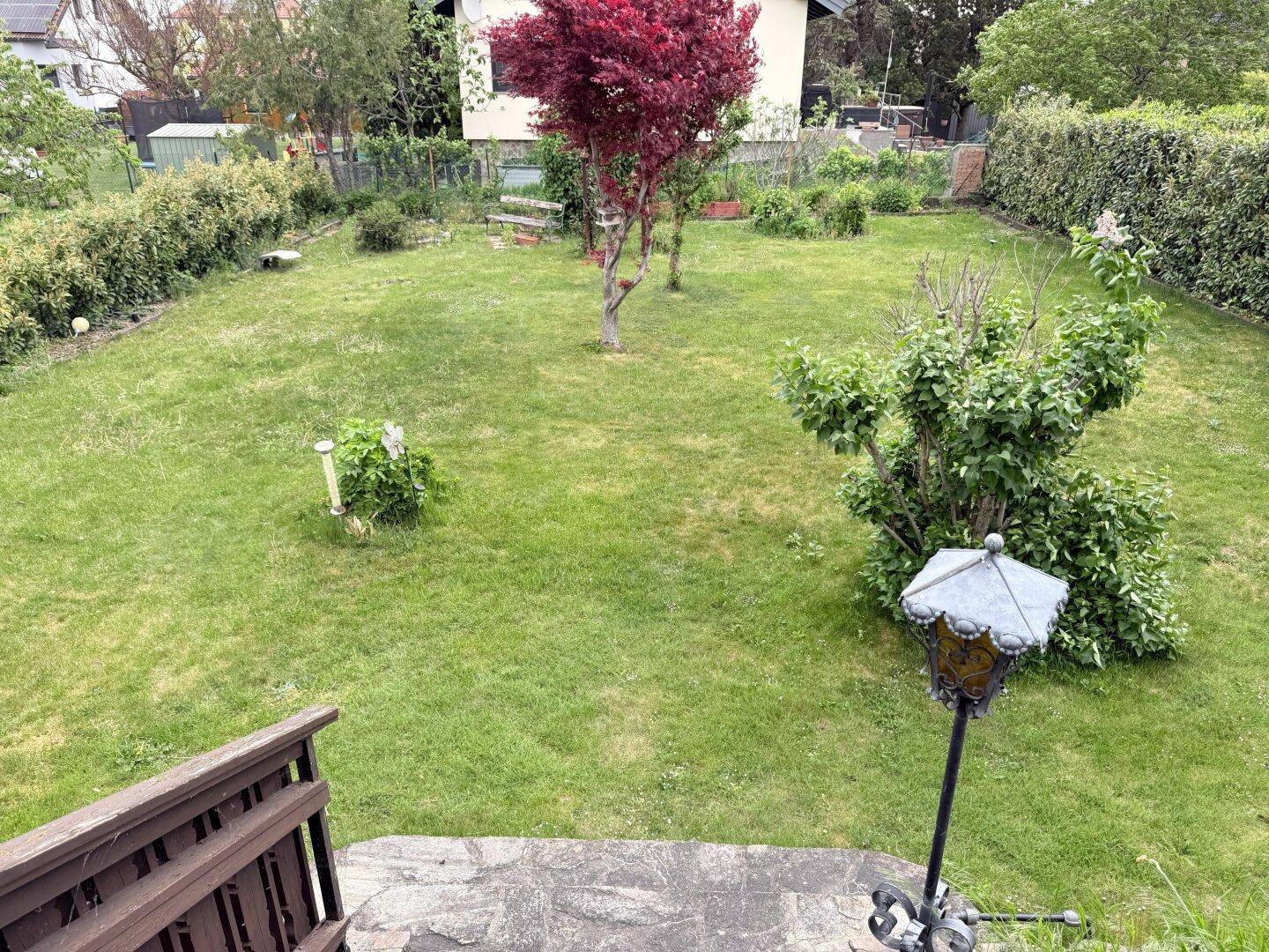Gepflegter Garten mit Rasenfläche, verschiedenen Bäumen und Hecken, von oben betrachtet.