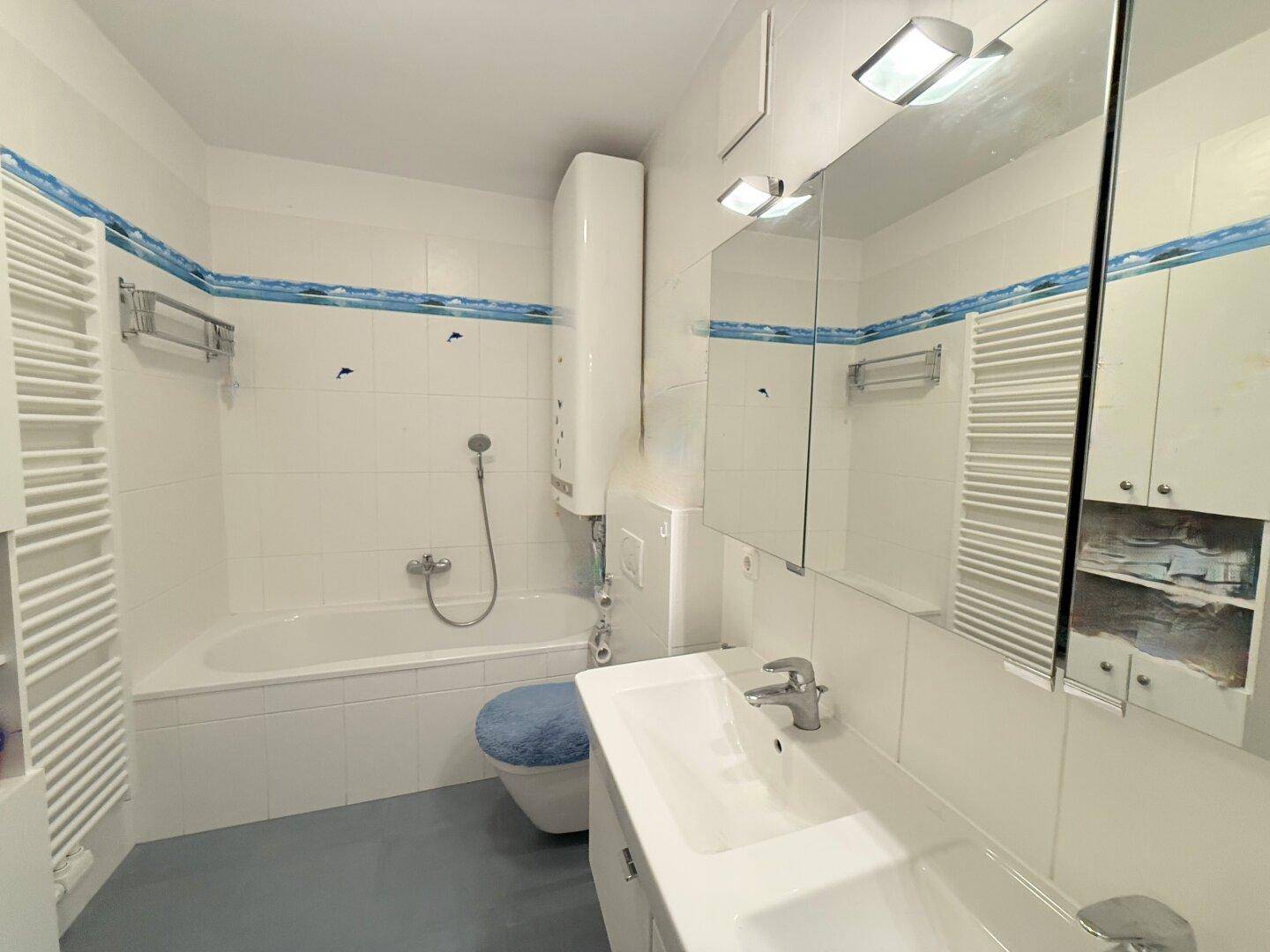 Helles Badezimmer mit Badewanne, Waschbecken und beheiztem Handtuchhalter.