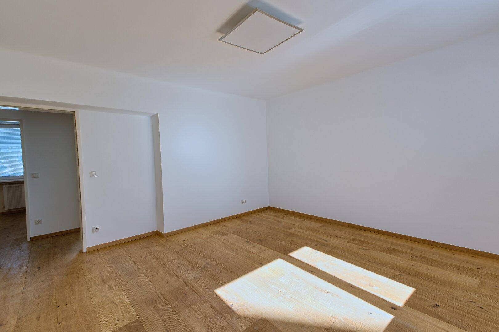 Geräumiges, leeres Zimmer mit Holzboden und hellem Tageslicht, ideal als Schlafzimmer nutzbar.