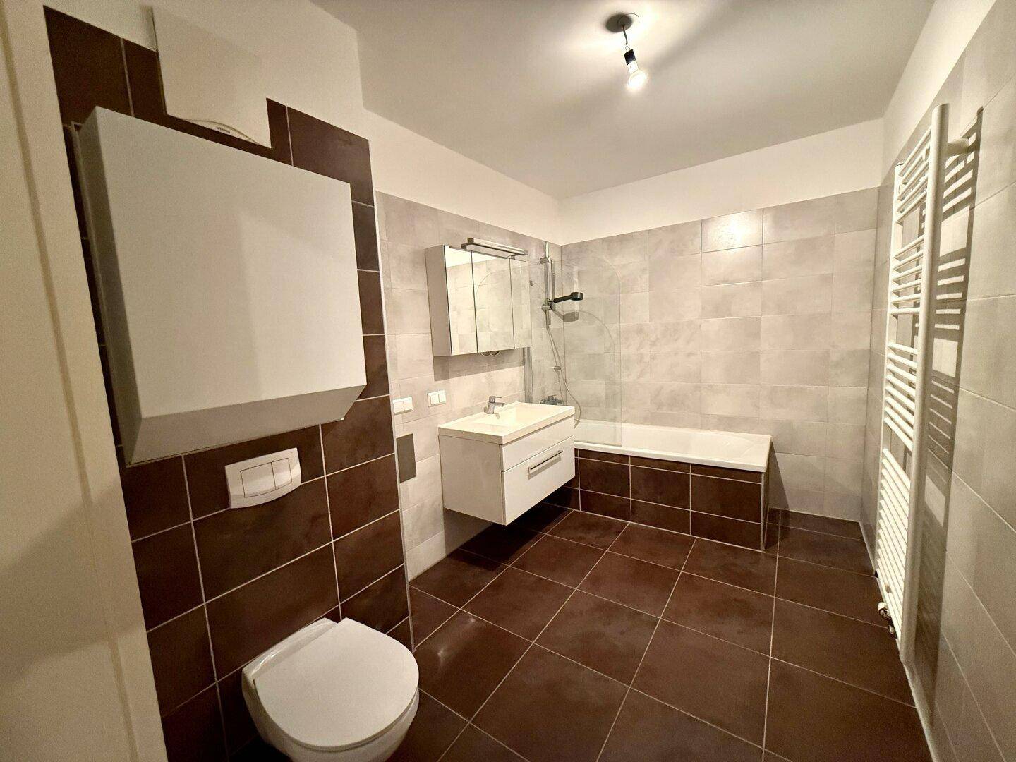 Modernes Badezimmer mit Badewanne, Dusche, WC und beheiztem Handtuchhalter.