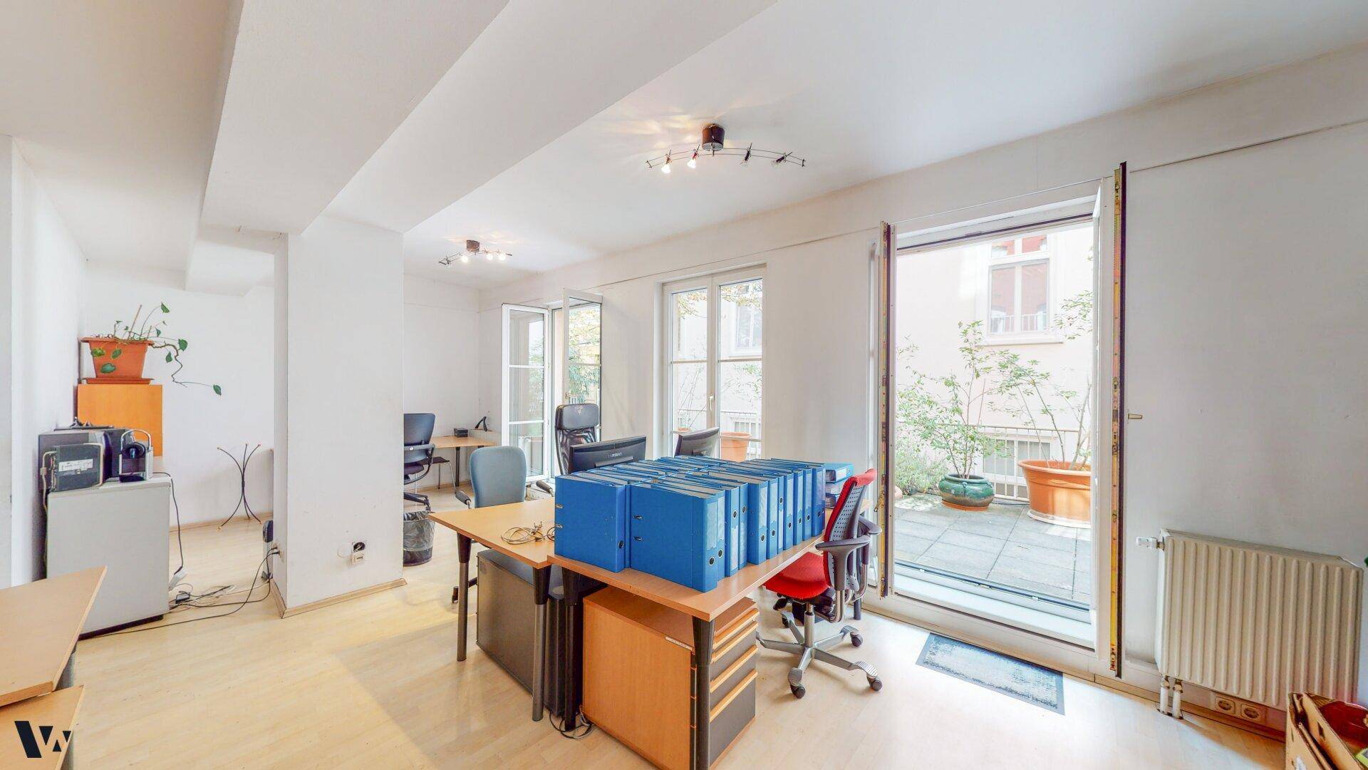 Großes Büro mit Zugang zu einer Terrasse, ausgestattet mit mehreren Schreibtischen und Aktenordnern.