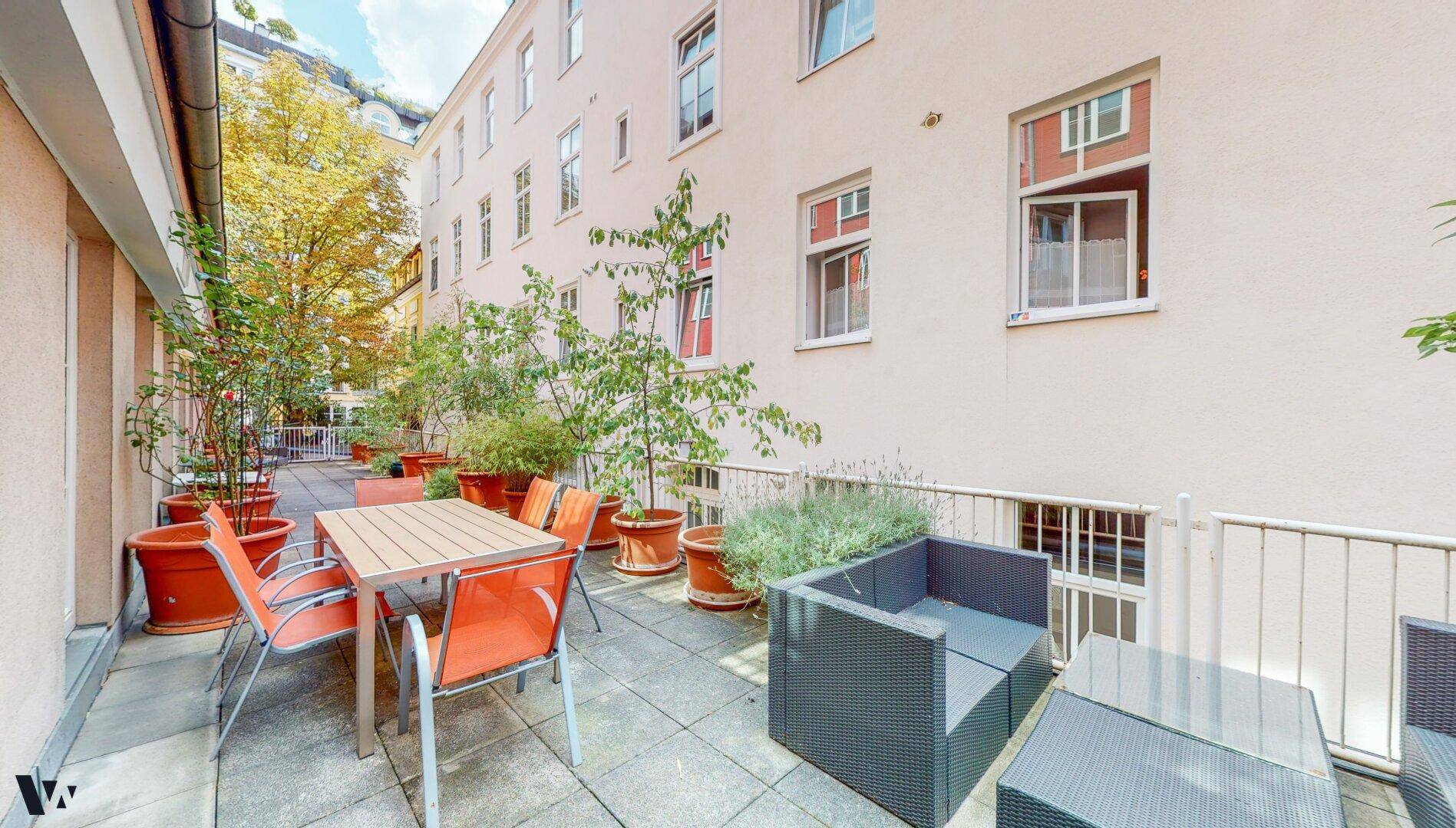 Große gepflasterte Terrasse mit Sitzgelegenheiten und Pflanzen, bietet viel Platz zum Entspannen.